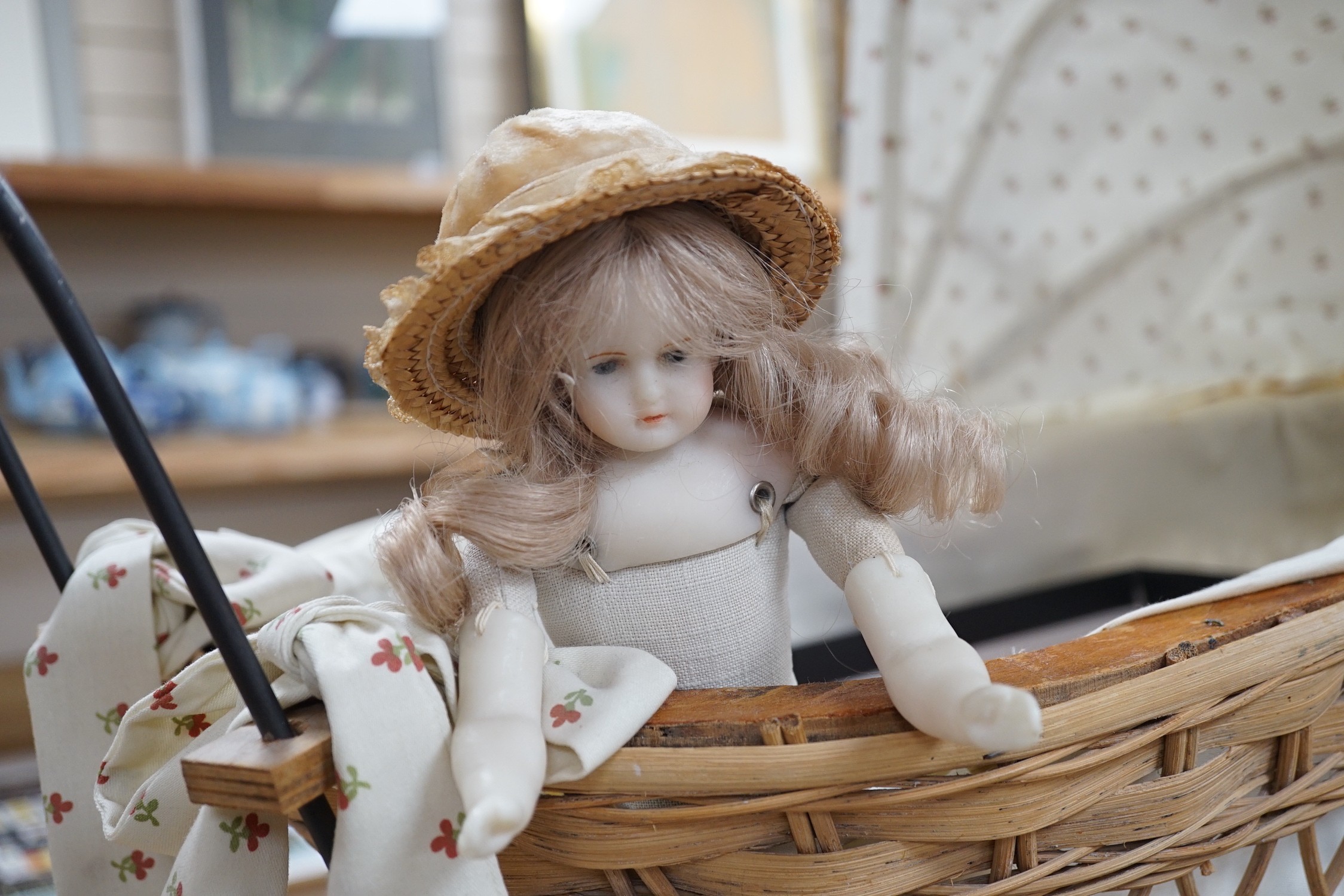 A small wax shoulder- head doll, small bisque doll and doll's accessories including a perambulator, etc.